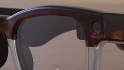 a close-up of a pair of brown smart glasses with a pinhole camera and AR display mounted in the corner
