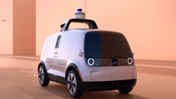 A small black and white self-driving van. It is boxy and has a LIDAR unit attached to the top. 