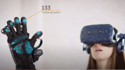a woman with a VR headset on with her palm raised towards the camera wearing a haptic glove