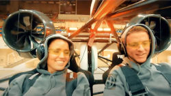 a man and woman are seated in an open frame aircraft