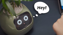A light green planter with an LCD screen for a face with cartoon text bubble that reads Hey!