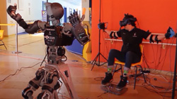 A telepresence avatar robot mimicking a human in the background.