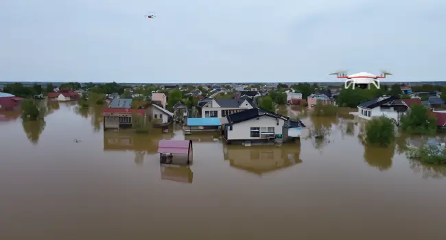Search and rescue drone flying over flooded area with houses.