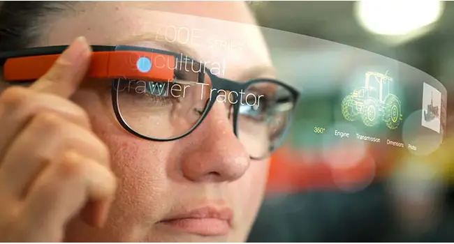 A person is pressing a button on the side of electronic glasses. A holographic display appears in front of the glasses.