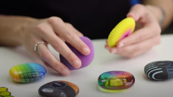A closeup of a person examining 6 oreo cookie size objects of different colors