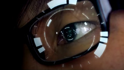 An extreme closeup showing one eye of a person wearing dark glasses with a futuristic focusing ring AR overlay targeting the center of the pupil