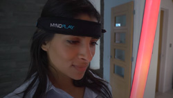 A person is wearing a headband staring at a red fluorescent tube.