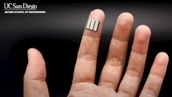 A closeup of a person's hand with a small device taped to the index fingertip.