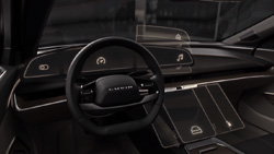 A view from the driver's seat show a black and silver minimalistic sedan dashboard. It has two displays, one where the instrument panel would be and the other a tablet size screen in the console at a 45 degree angle