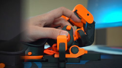 A closeup of a person's left hand resting on an orange and black keyboard that looks like a human hand facing up.