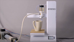 a white desktop 3D printer is printing a large drinking cup made of clay