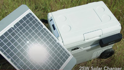 A closeup of a portable cooler with wheels sitting next to a solar panel about the same width and length