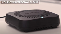A closeup view of a small square black device with vent holes on top. Text reads Your Own Personal Cloud
