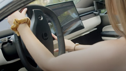 A closeup of a person in behind the wheel of a car with a large display in the center console.