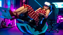 A person wearing a vr headset is smiling in a chair that is tilted back and is supported from below