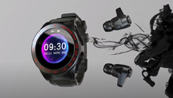 A closeup of a graphite black colored smartwatch floating in mid-air with 2 earbuds on the right side. The watch has sockets on the side that the earbuds fit into. The face of the watch has 9:30 displayed in white and is backlit with several shades of purple.